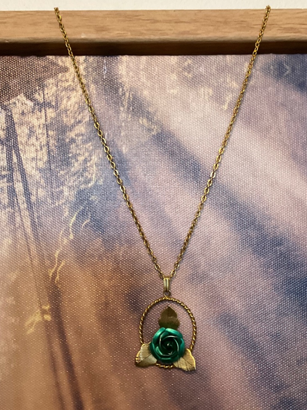 Gold toned pendant necklace with a green metallic rose and golden leaves.